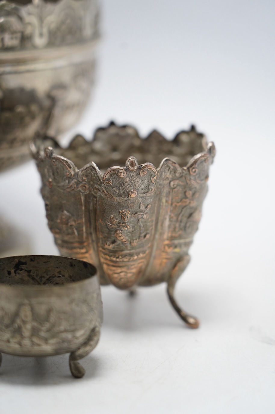 An Indian repousse white metal pedestal bowl, diameter 15.5cm (a.f.), a similar mug, small vase, condiment and small beaker. Condition - poor to fair